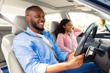 Seyahat kavramının tadını çıkarıyorum. Gülümseyen yakışıklı Afro-Amerikan adam modern lüks araba kullanıyor, mutlu güzel kadın ön koltukta oturuyor, yola bakıyor, yolculuğa çıkıyor.