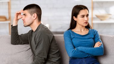 Quarrels Karantinası. İzolasyon sırasında tartıştıktan sonra birbirlerini görmezden gelen çift evlerindeki koltukta ayrı oturuyorlar.