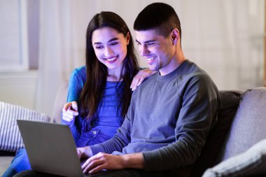 İnternetten alışveriş. Çift dizüstü bilgisayar kullanıyor, satın almayı tartışıyor ve rahat oturma odasında kanepede oturuyor.