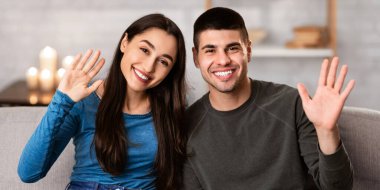 Hoş geldiniz. Gülümseyen bir çift evdeki kanepede oturuyor ve el sallayarak selam veriyorlar.