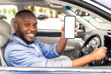 Lüks bir arabada oturan neşeli genç siyah adam, cep telefonunu beyaz ekranlı gösteriyor, navigasyon için en yeni mobil uygulamayı öneriyor, maket. Otomobil, sürüş ve modern teknolojiler