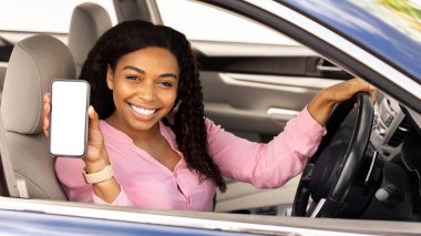 Elinde boş ekranla akıllı telefonu tutan mutlu siyah kadın sürücü, taklit et, cep telefonunu beyaz ekran ile gösteren kadın, navigasyon için mobil uygulama kullanıyor, şehirde geziniyor, bedava kopyalama alanı