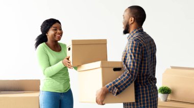 Yer değiştirme günü. Karton kutular taşıyan mutlu Afrikalı Amerikalı bir çiftin portresi, neşeli siyah eşlerin yeni bir daireye taşınması, eşyalarının paketlenmesi ve her bir Otrher 'a gülümsemesi,