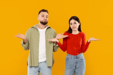 Kafkasyalı genç bir çift belirsizlik ifadeleriyle yan yana duruyor, gündelik kıyafetlerle. Parlak sarı bir arka plana karşı dururlar, oyuncu bir sevgi ve bağlantı sergilerler..