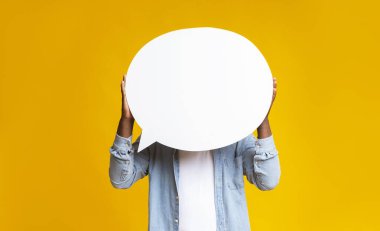 Tanımlanamayan siyah adam kafasının önünde boş bir konuşma balonu tutuyor sarı stüdyo arka planında, boşluğu kopyalıyor.