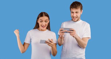 Kazan Kavramı. Neşeli genç adam ve kadın birlikte oynuyorlar ve akıllı telefonlarda video oyunlarında yarışıyorlar.