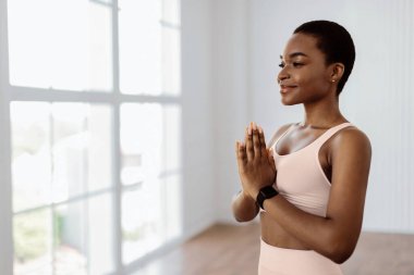 Farkındalık. Sakin gülümseyen sporcu kadın sporcunun portresi dua ederken el ele tutuşuyor, avuç içlerini birarada tutuyor, meditasyon yapıyor, Kundalini Yoga yapıyor, boş fotokopi alanlarına bakıyor.