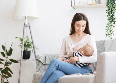 Eksiklik Konsepti. Güzel anne yeni doğmuş bebeği evdeki kanepede emziriyor.