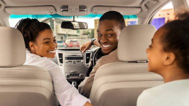 Afrika kökenli Amerikalı bir ailenin yeni arabalarında oturup birbirlerine gülümseyip yaz yolculuğunun tadını çıkarmalarını izlemek. Otomobil Kiralama ve Satın Alma Konsepti. Seçici Odaklanma