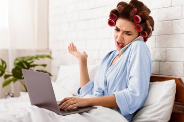 Memnuniyetsiz ev hanımı cep telefonuyla konuşuyor dizüstü bilgisayarını evde yatağında kullanıyor. Memnun Olmayan Müşteri Konsepti