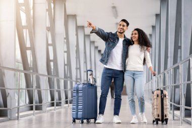 Birlikte seyahat ediyoruz. Havalimanı Terminali 'nde bavullarıyla ayakta duran genç ve mutlu Arap Çiftin Portresi, Romantik Ortadoğu Eşleri Uçuşu Bekliyor, Elle Yanyana Gösteren Adam, Uzayı Kopyala