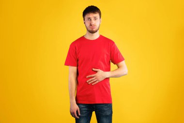 Genç erkek manken karnına dokunuyor, doyurucu bir yemek yedikten sonra doygunluk hissediyor, iştahı yerinde.