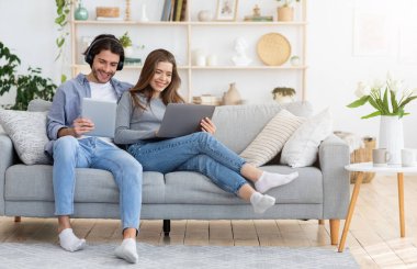 Genç aile hafta sonunu evde bilgisayar, tablet ve boş alan kullanarak geçiriyor.