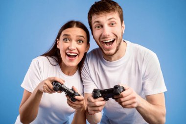 Birlikte video oyunu oynayan heyecanlı genç çift Pastel Mor Stüdyo Duvarı 'nda izole edilmiş