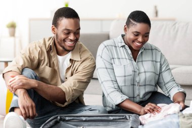 Tatil için aile bavulu. Mutlu Siyah Eşler Evdeki Oturma Odasında Birlikte Seyahate Hazırlanıyor. Afro-Amerikalı Turistler Valizli Poz Veriyor