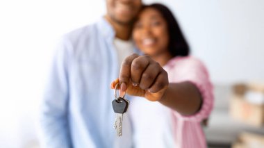 Aile konutları. Mutlu Afro-Amerikan eşleri yeni evin anahtarını, seçici odak noktasını, sığ derinliğini tutuyorlar. Gayrimenkul, mülkiyet ve ipotek