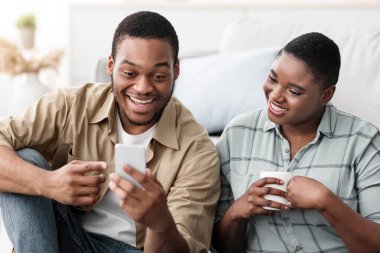 Seyahat Başvurusu. Online Akıllı Telefon Rezervasyon Biletleri Kullanan ve Evdeki Bavulun Yanında Oturan Siyah Turistler ve İnternet Cep Telefonu Planlama Tatilleri. Gezginler için Mobil Uygulama