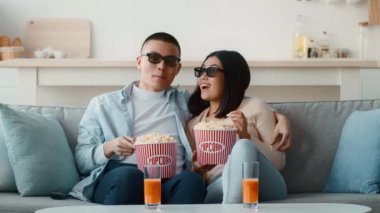 Rahat bir kanepede, güneş gözlüğü takıp patlamış mısır ve portakallı içecekleri paylaşan bir çift. İçerde rahat bir film gecesinde eğlendirici bir atmosfer yaratıyorlar..