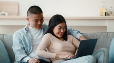 Genç bir adam ve bir kadın bir kanepede yakın oturuyorlar, bir dizüstü bilgisayarla meşgul olurken birbirlerine gülümsüyorlar. İçerideki rahat ortam aktiviteleri için samimi bir atmosfer yaratıyor..