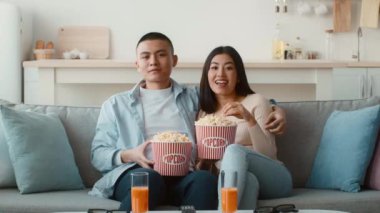 Genç bir çift rahat bir kanepede oturur ve eğlenceli bir film gecesini paylaşır. Birlikte televizyon izlerken büyük patlamış mısır kovaları ve ferahlatıcı içecekler tutuyorlar..