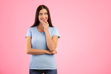 İyi teklif. Fotokopi odasına bakan, parmaklarıyla çenesine dokunan, sarı stüdyo arka planında izole edilmiş rüya gibi gülümseyen genç bayanın portresi. Düşünen ve karar veren düşünceli kadın