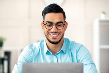 Bilgisayarlı genç Arap işadamı modern ofiste sunum yapıyor. Uzak iş, iletişim ve iş eğitimi için bilgisayar kullanan bir şirket çalışanı.