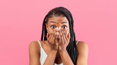 Korkmuş genç Afro-Amerikalı kadının portresi yüzünü pembe stüdyo arka planıyla kapatıyor. Korkmuş bin yıllık siyah kadın fobisinden muzdarip,