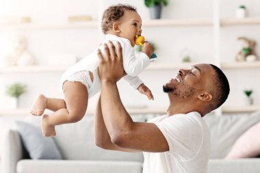 Mutlu Aile. Siyah Baba 'yı sevmek, sevimli bebeğini havaya kaldırmak, Afrikalı Amerikalı bir çocuğun tatlı çocuğuyla evde bağ kurması, birlikte vakit geçirmenin tadını çıkarması,
