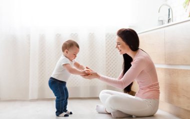 Doğru ebeveynlik. Anne mutfak katta yürümeye başlayan ile oynarken, sebze, boş alan okuyor