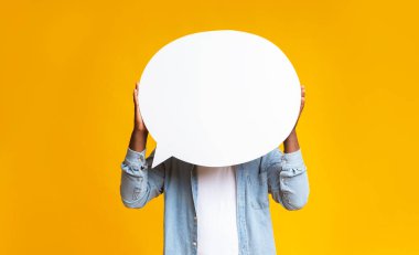 Tanımlanamayan siyah adam kafasının önünde boş bir konuşma balonu tutuyor sarı stüdyo arka planında, boşluğu kopyalıyor.