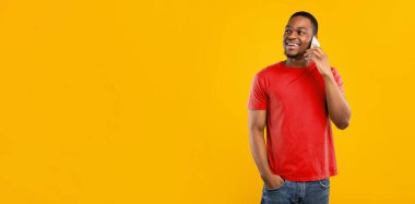 Telefondan konuşan mutlu Afro-Amerikalı adam elini cebine sokup Sarı Stüdyo Arkaplanı üzerinden cep telefonuyla iletişim kuruyor. Modern Mobil İletişim Konsepti