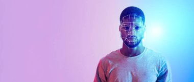 Genç bir adam renkli bir arkaplana karşı duruyor, yüzünü dijital yüz tanıma teknolojisiyle renklendiriyor..