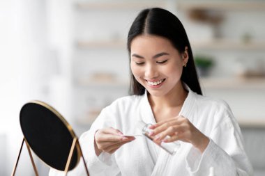 Güzel, genç Asyalı bir kadın yüzünü temizliyor. Pamuk pedlerle, temizlik ürünleriyle, yatak odasının içiyle. Mutlu Koreli kadın evde yüz toneri ve pamuk pedi kullanıyor, boş yer.