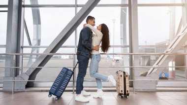 Havalimanı Terminali 'nin yanında sarılan genç Orta Doğulu çift, bavullu mutlu Arap eşler, balayı seyahati için bekliyor, fotokopi alanı ile yan görünüm