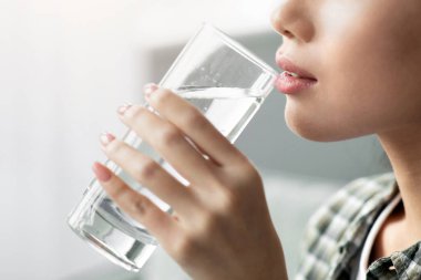 Günlük kıyafet giymiş, kaynak suyu içen, yan görüş alan, fotokopi çeken Asyalı genç bir kadın. Bir bardak suyla Koreli güzel bir bayan. Susuzluk, su içme, sağlıklı yaşam tarzı konsepti.