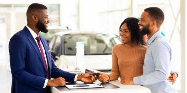 Araba satın alma. Yeni otomobil, genç Afro-Amerikan eşler satın aldıktan sonra mağaza müdüründen anahtar alan, modern Showroom 'da araba seçen, satıcıya gülümseyen mutlu siyah çift.