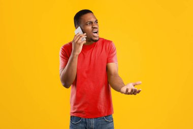 Öfkeli Afrikalı Amerikalı Telefonda Konuşan Sinirli Hareketli Cep Telefonu Konuşması Sarı Stüdyo Arkaplanı 'nın başında duruyor. Mobil İletişim Sorunu