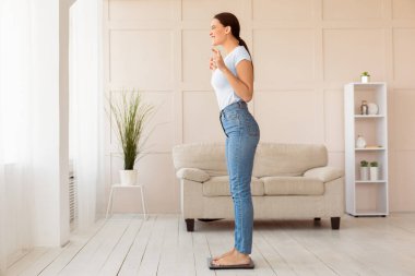 Kilo kaybı. Kilo tartısında kendini tartan genç bir kadın parmaklarını evde zayıflatmak için dua ediyor. Boş Alan