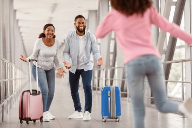 Havaalanında buluşma. Küçük siyah kız havaalanına vardıktan sonra ailesinin yanına koşuyor. Tatil yolculuğundan eve dönüyor. Mutlu erkek ve kadın kızlarını kucaklamaya hazır.