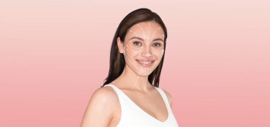 Bir kadın kendine özen gösteren bir cilt bakımına girer, gülümser ve rahatlar. Yumuşak pembe bir arka plana karşı duruyor, güzellik ve sağlığa olan bağlılığını gösteriyor..