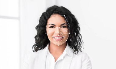 Kıvırcık saçlı bir kadın, yüz tanımlama teknolojisi yüz hatlarını belirlerken kendine güvenerek gülümser. Arkaplan parlak ve minimalist, ifadesini vurguluyor..