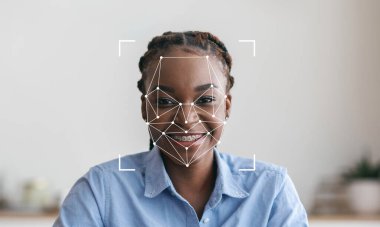 Saçları örgülü neşeli bir birey içeride oturur ve yüz tanıma sürecine girer. Çevre parlak ve minimalisttir, konuların ifadesini vurgular..