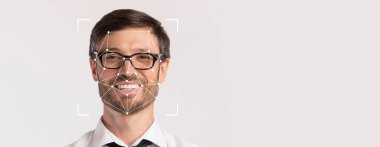 Gözlüklü gülümseyen bir adam, yüz tanıma teknolojisini ön plana çıkaran boş bir arkaplanda belirgin bir şekilde yer alıyor. İfadesi, dostluğu profesyonel bir bağlamda iletiyor..