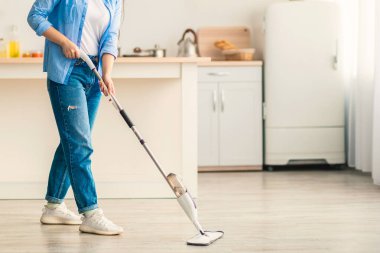 Ev hanımı. Sıradan bir kadının portresi ahşap döşemeleri yıkamak için su spreyi ve temizlik malzemesi ile doldurulabilir şişe kullanmak. Bulanık Mutfak Arkaplanı, Beleş Kopya Alanı, Modern İçişleri