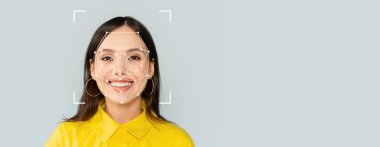 Tarafsız bir geçmişe sahip gülümseyen bir birey, yüz tanıma teknolojisi tarafından analiz ediliyor, modern ortamlarda tanımlama yöntemlerinin uygulanmasını gösteriyor.