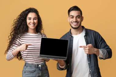 Web sitesi modeli. Çevrimiçi reklam için fotokopi alanı gösteren Milenyum Orta Doğulu erkek ve kadın, sarı arka planda poz veren mutlu genç Arap çift.