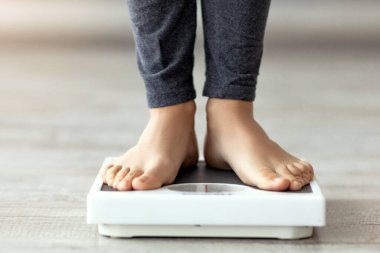 Tanınmayan Hintli kadın terazinin üzerinde duruyor, ağırlığını içeride kontrol ediyor, ayaklarına yakın çekim yapıyor. Bin yıllık kadın zayıflama diyeti yapıyor, kilolarını kaybediyor, sağlıklı bir hayat sürüyor.