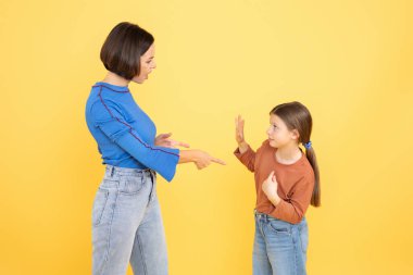 Bir anne ve reşit olmayan kızı, sevgi ve yakınlık göstererek canlı bir sohbet ederler. Parlak sarı arka plan, bağlantılarını ve neşeli etkileşimlerini vurgular..