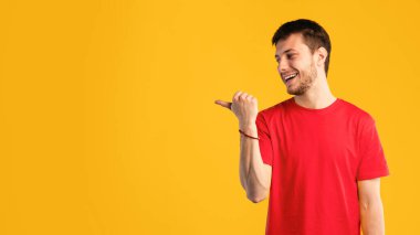 Harika bir öneri. Mavi Stüdyo Arkaplanı 'nda izole edilmiş ve parmağını gösteren heyecanlı gülümseyen genç adam portresi. Duygusal Erkek Modeli Boş Alan ve Sancak Göstergesi