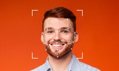 Genç bir adam, yüz tanıma teknolojisi özelliklerini turuncu bir arka planda tararken kendine güvenerek gülümsüyor. Yüksek teknolojili tanımlama modern gelişmelerin açık ve net bir göstergesidir..